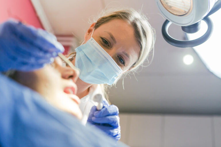 Photo of a concerned looking man with a recent dental implant, touching his cheek in discomfort. No text on the image.